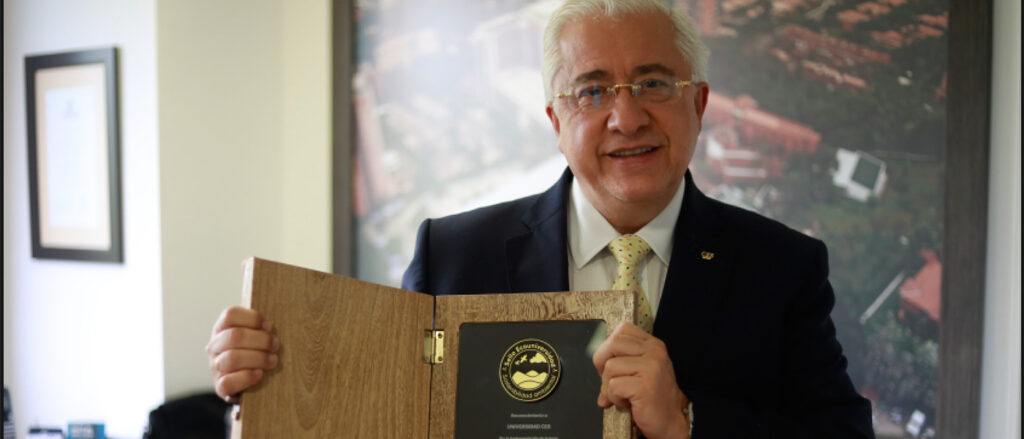 imagen del rector sosteniendo el premio de reconocimiento